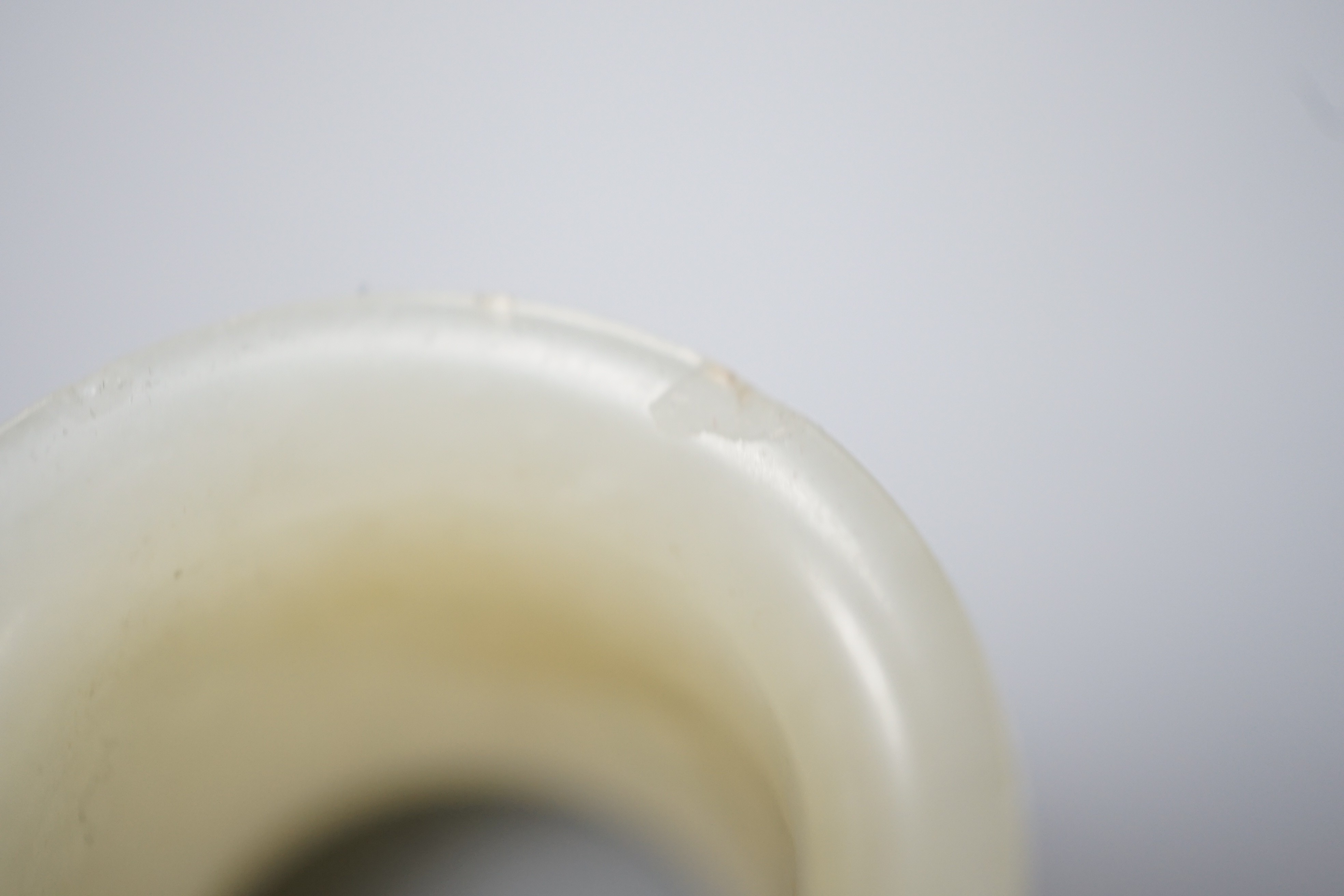 A 19th century Chinese pale celadon jade archer’s thumb ring, inscribed, 3 cm diameter